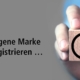 Die eigene Marke registrieren mit Hand, die Würfel mit Aufdruck Registered Trademark hält.