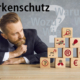 Unternehmer vor Pyramide aus Fragen zu Markenschutz