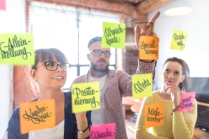 Personen beim Positionierungsworkshop vor Glaswand mit Zutaten für Markenpositionierung als Dienstleister in freien Berufen